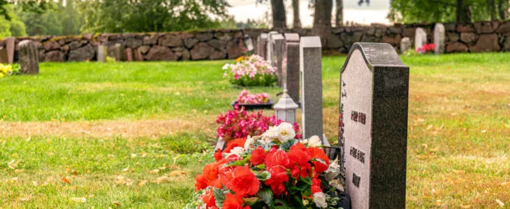 Row of gravestones with colorful flowers at a well cared cemetery in Sweden